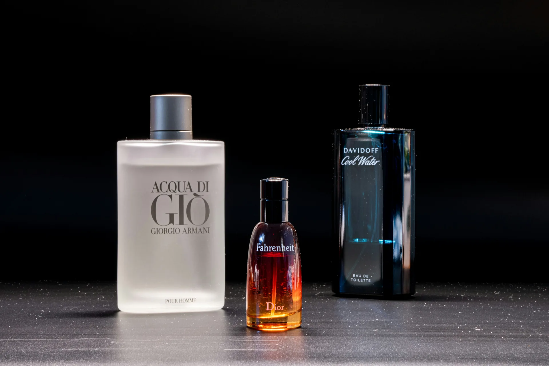 Acqua di Gio, Dior Fahrenheit and Davidoff Cool Water bottles against a dark backdrop