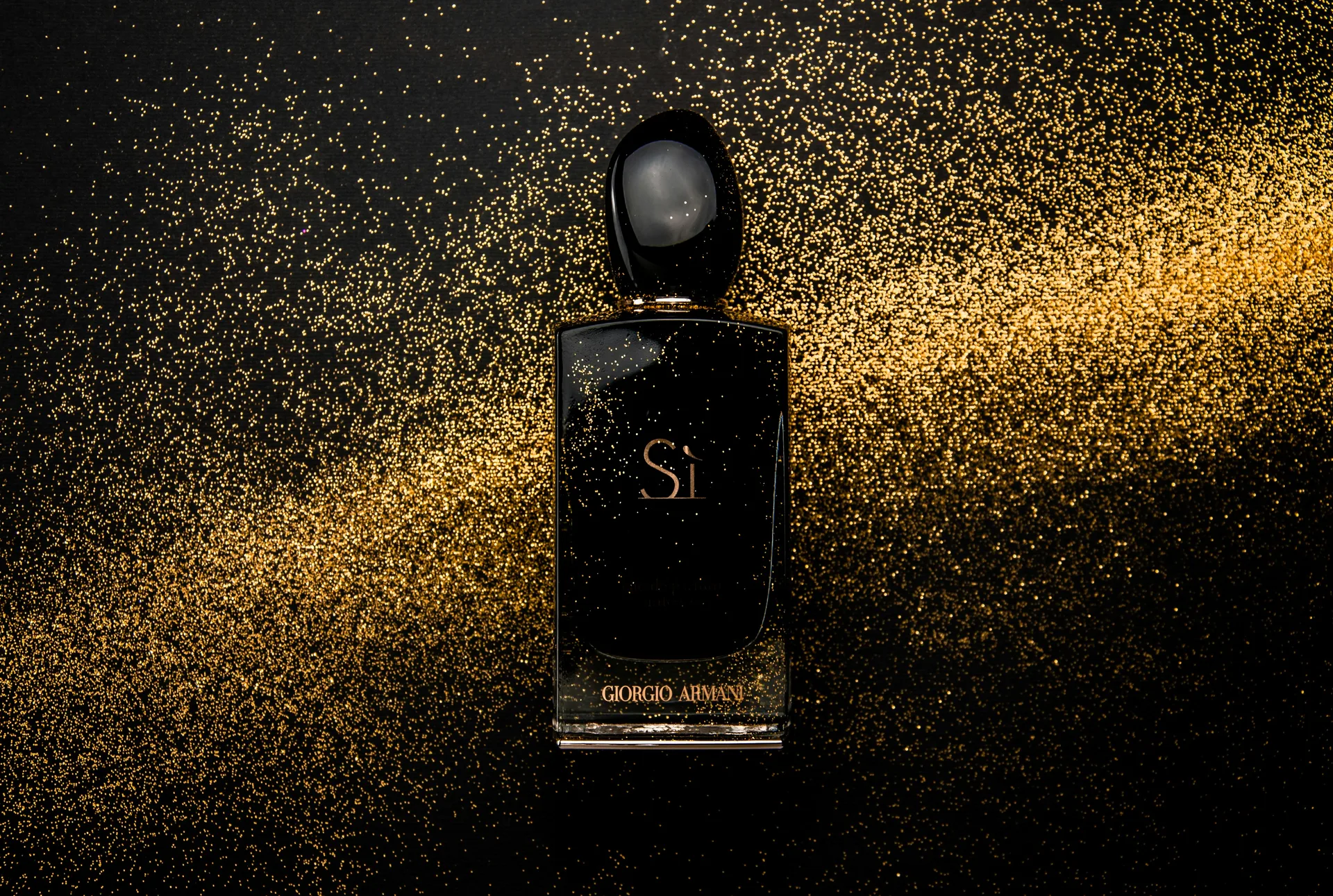 A Giorgio Armani Sì perfume bottle surrounded by golden shimmer